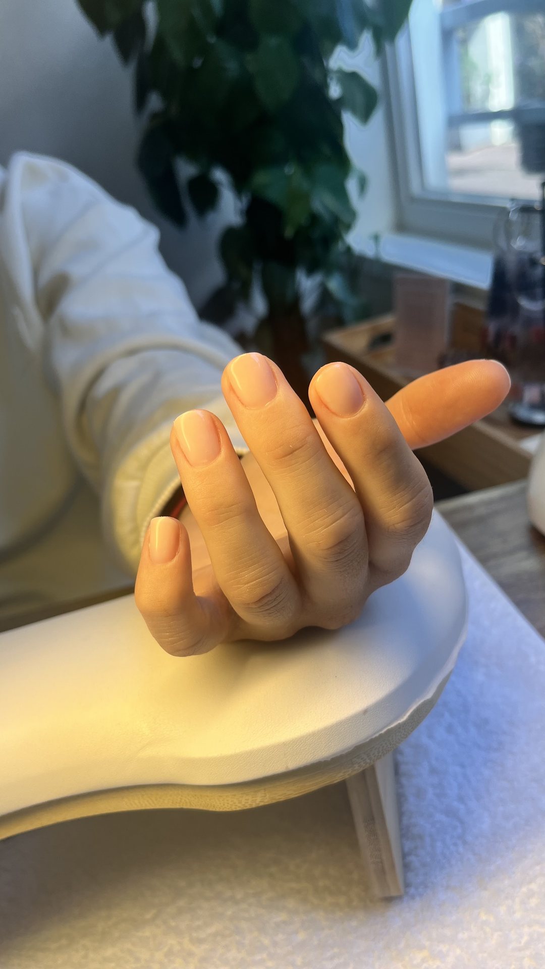 Perzikkleurige nagels op de handsteun in warm licht